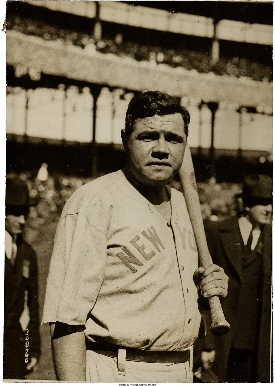 Babe Ruth holding a bat in front of a crowded grandstand, early 1920s